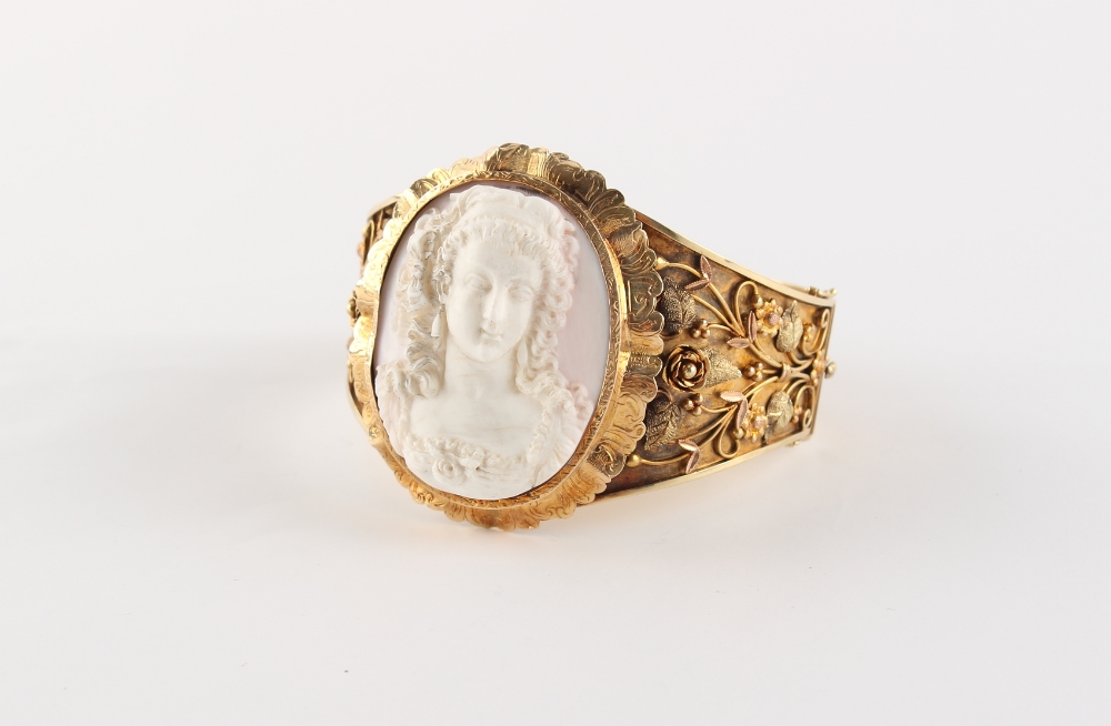 A good late 19th century three colour gold (tests 14ct) hinged bangle set with a carved shell