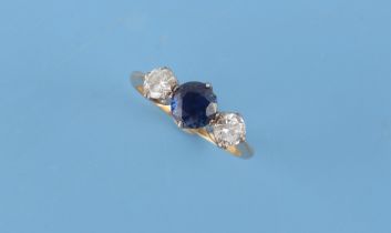 An 18ct yellow gold sapphire & diamond three stone ring, the centre round cut sapphire weighing