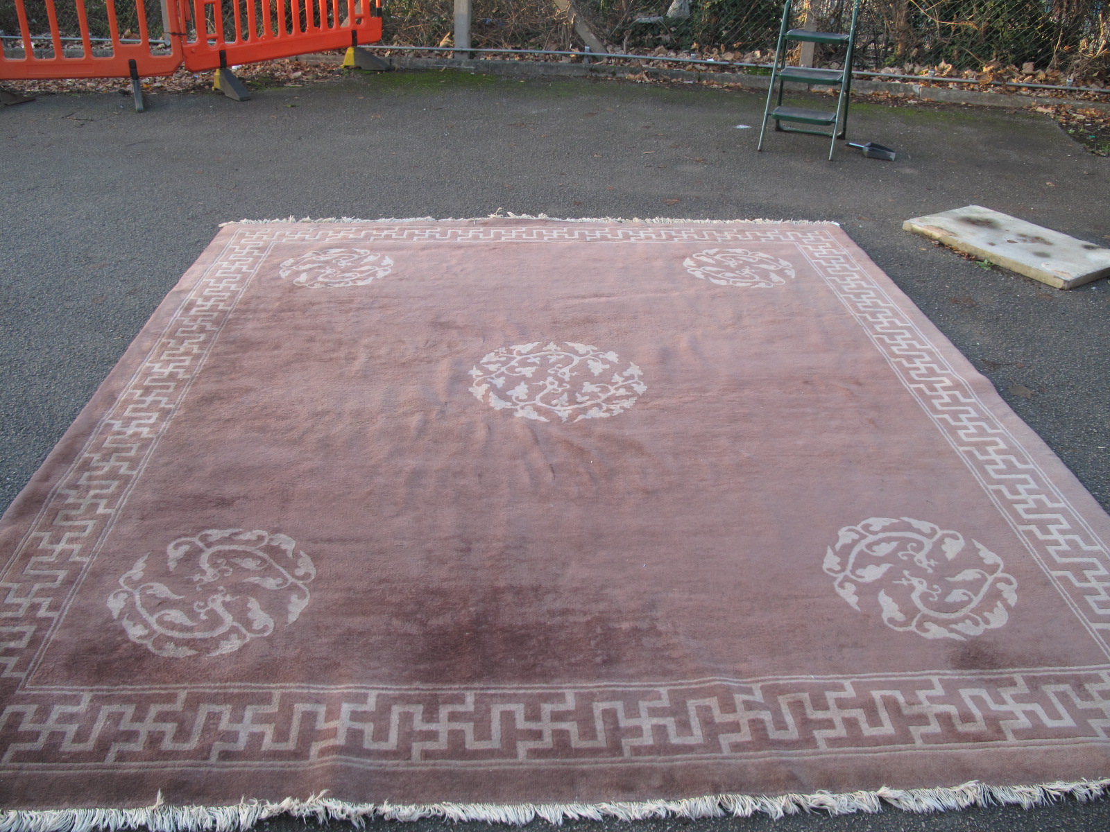 A Chinese Wool Tassled Carpet, with floral motifs, within Swastika border, on brown ground, no