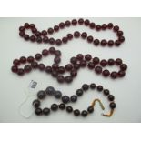 A Cherry Coloured Bead Necklace, of uniform roundel form, 35cm long, together with another; and a