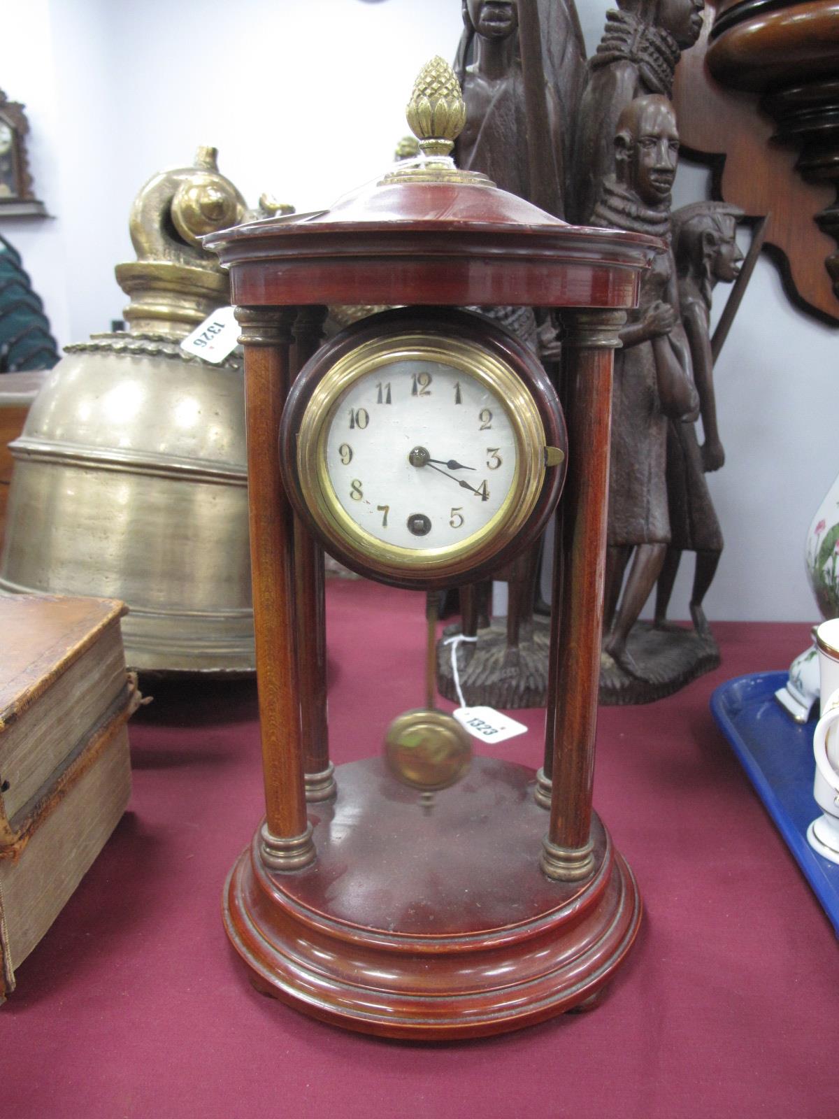 A XX Century Stained Mahogany Mantel Clock, with finial top, column supports, round dial stepped