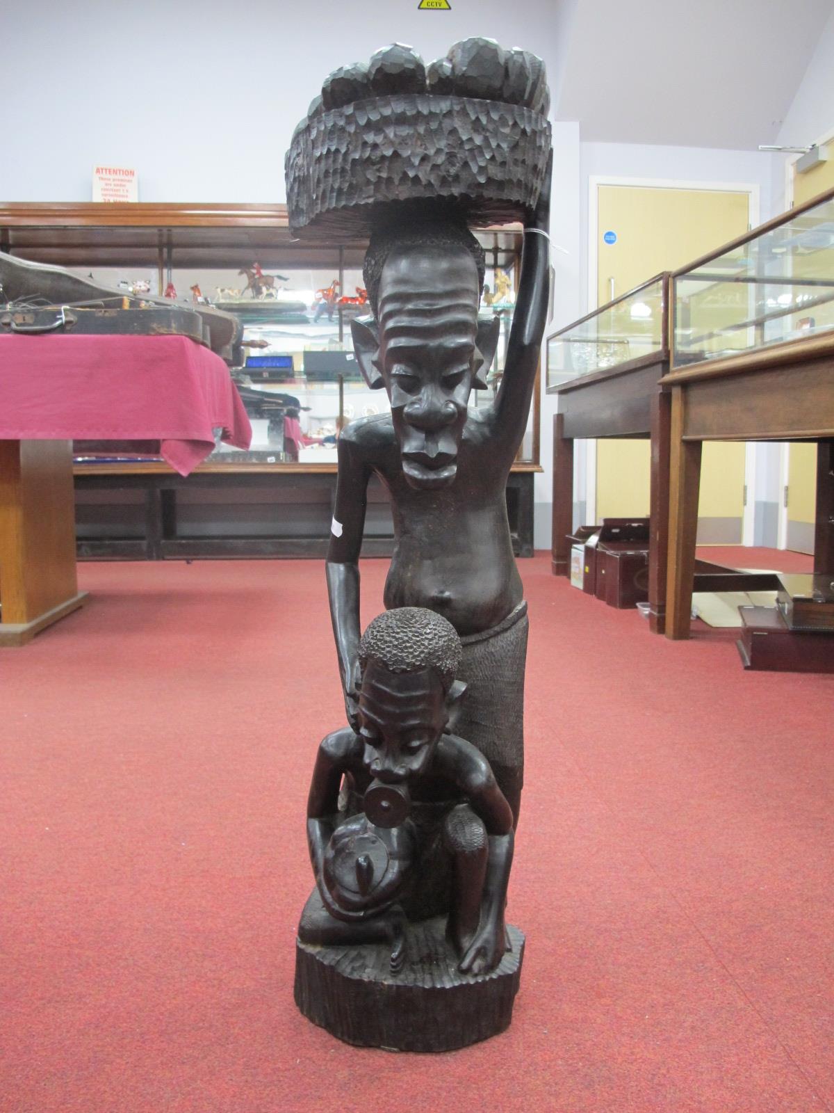 Ethnographica, carved hardwood standing male figure carrying basket on head, with seated man man