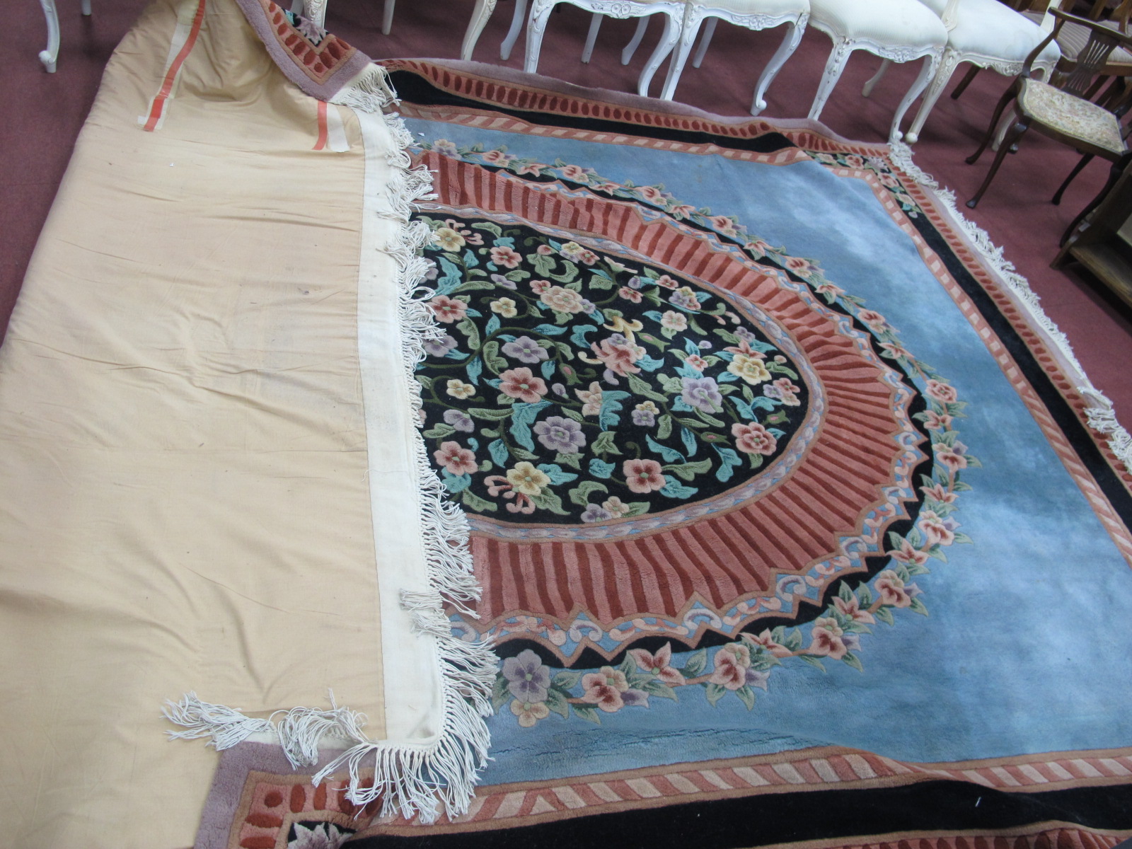 A Chinese Wool Tasseled Carpet, with linear and floral circular centre panel on pale blue ground,