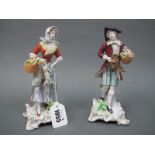 A Pair of Sitzendorf Porcelain Figures of a Lady and Gentleman, she carrying a basket and holding
