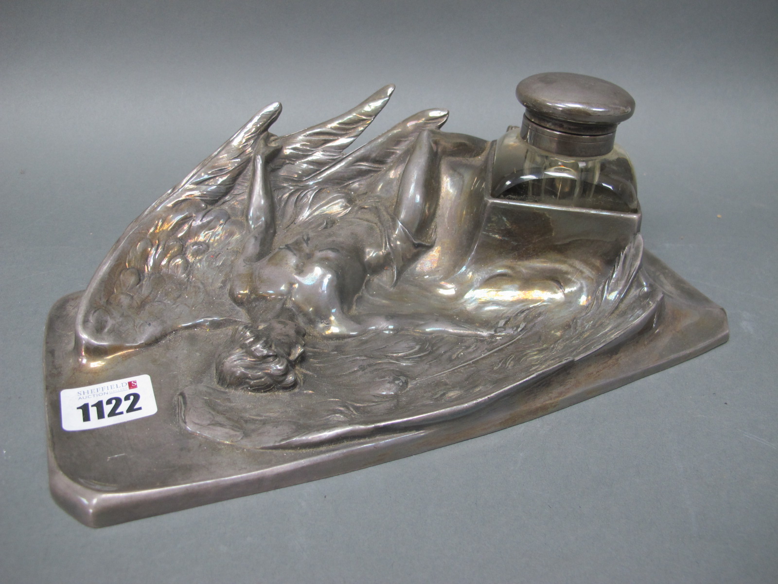 An Early XX Century Pewter WMF Style Desk Standish, the shaped rectangular base cast with a winged