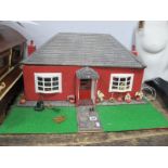 Dolls Bungalow, red painted with bowed windows, on green plinth complete with furnishings and