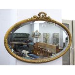 An Early XX Century Oval Bevelled Wall Mirror, with gilt wood and plaster surround with foliate