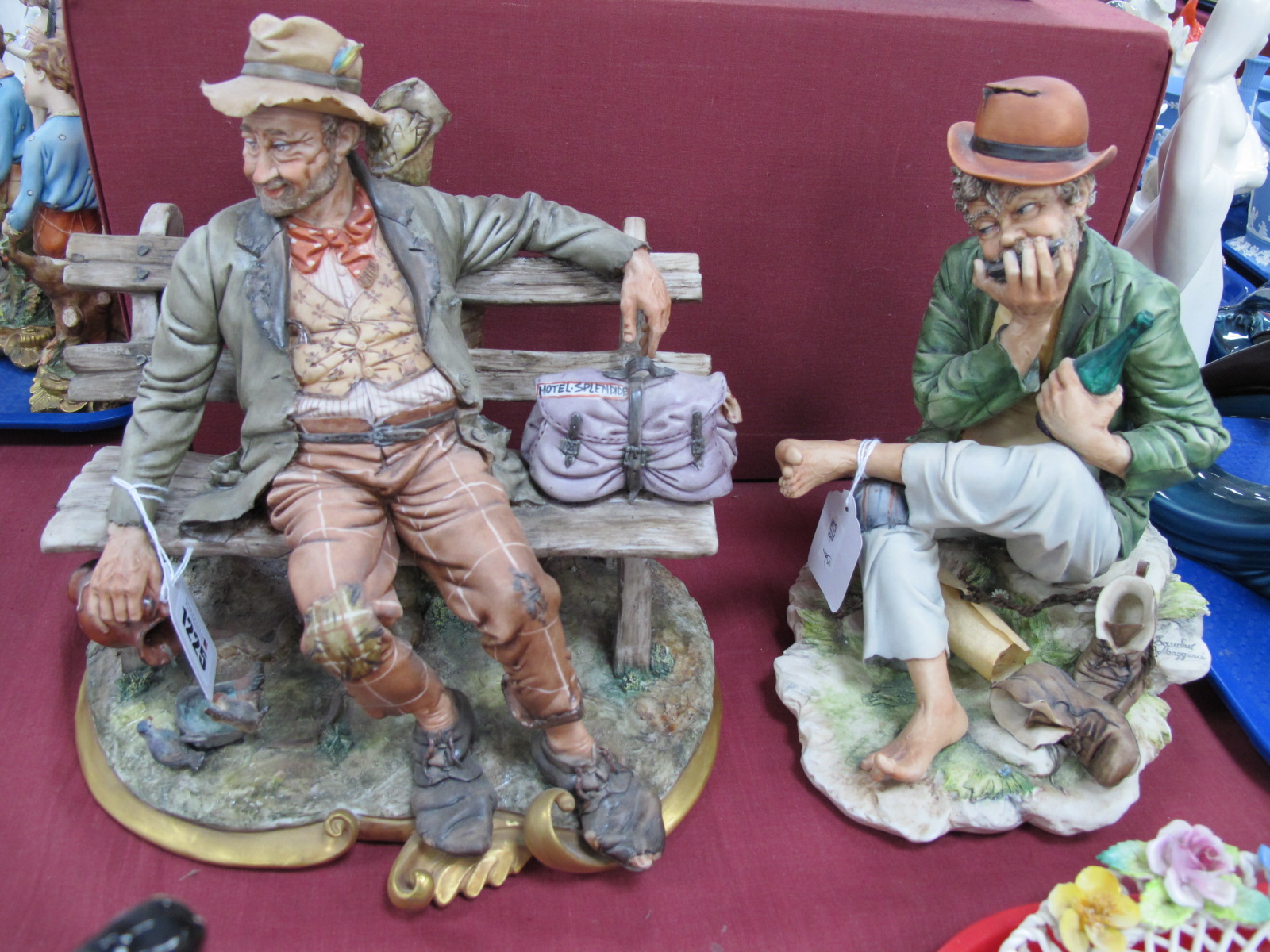 Capodimonte Figure of a Tramp on a Bench, signed Volta, another of a tramp playing mouth organ by