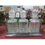 A Silver Plated Tantalus, housing three cut glass decanters, 34cm wide.