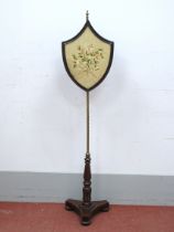 A XIX Century Mahogany Fire Screen, the shield shaped floral woolwork tapestry screen on brass pole,