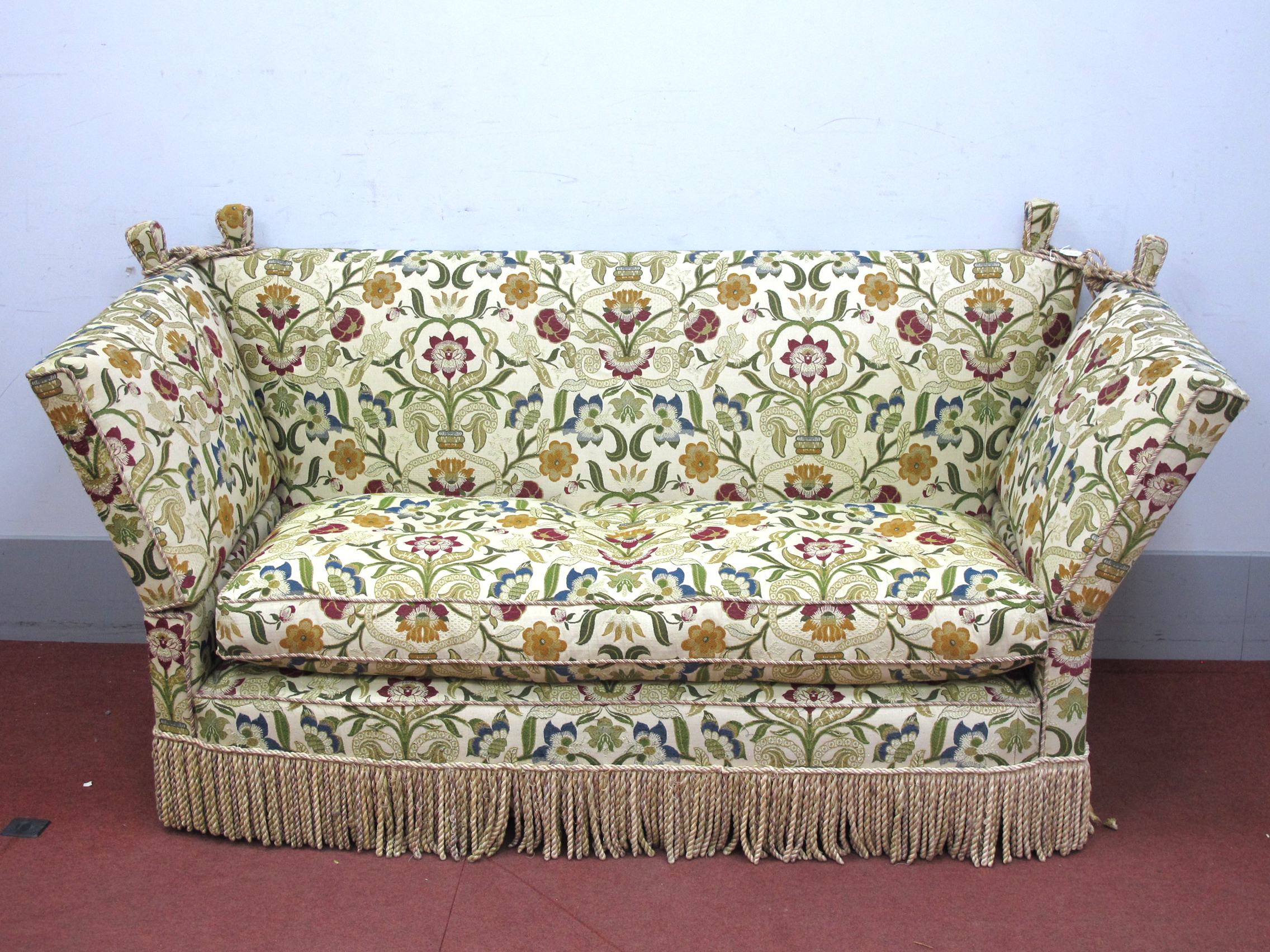 A Knole Settee, upholstered in a floral fabric with tassled fringing and cord ties to the corner