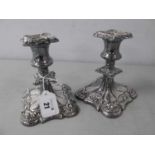 A Pair of Decorative Plated Dwarf Candlesticks, decorated in relief with foliate scrolls, on
