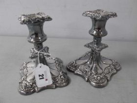 A Pair of Decorative Plated Dwarf Candlesticks, decorated in relief with foliate scrolls, on