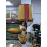 A vintage painted plaster table lamp as a mid XX century spanish lady holding a tamburine on a black