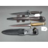 Two Fairburn Sykes Commando Style Knives, both with cross guards, spearpoint blades, and leather
