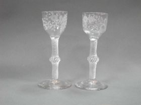 A Pair of XVIII Century Drinking Glasses, the engraved ogee bowls raised on knopped air twist