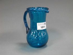 A Turquoise Glass Jug, the speckled body with bulbous lower section and fold over rim, 12cm high.