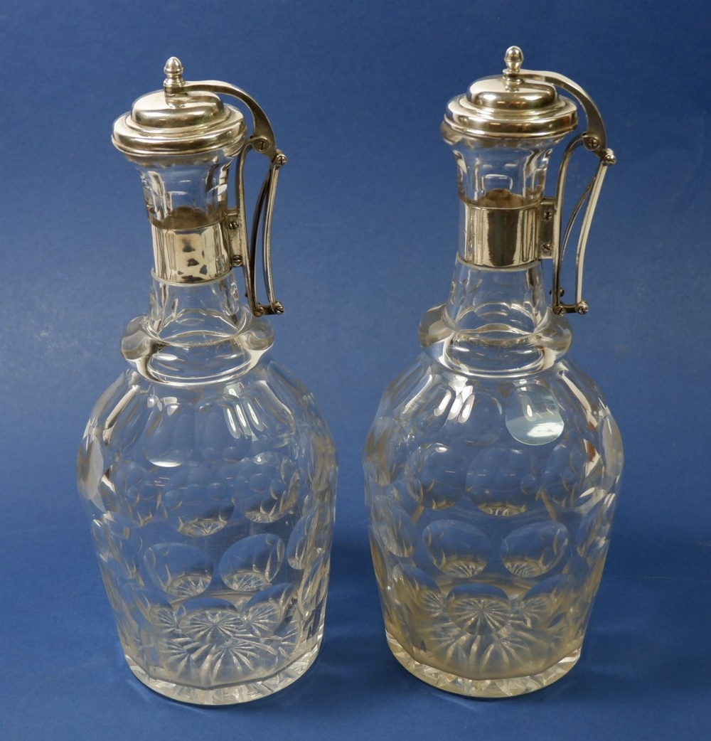 A pair of Edwardian silver plated facet cut decanters with silver plated press action hinged lids