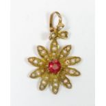 An Edwardian 9 carat gold floral pendant set red stone to centre and seed pearls to petals, 1.5cm