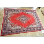 A large woollen Persian style carpet with floral medallion and spandrels on a red ground, 354 x