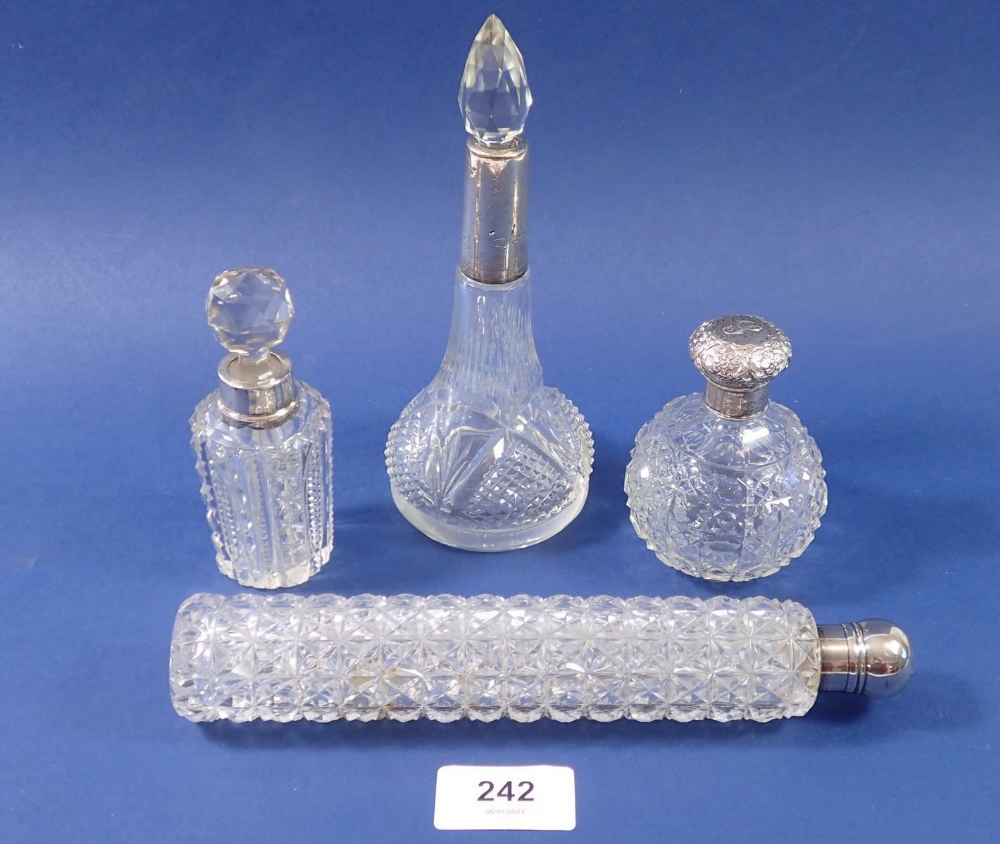 A Victorian cut glass toiletry bottle with silver lid, 21cm long and three other toiletry bottles