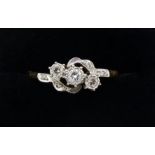 An 18 carat gold and platinum set three stone crossover ring on diamond chip shoulders, size P