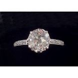 A large platinum set solitaire diamond ring, the diamond measuring 2.33cts on diamond set shoulders,