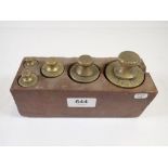 A set of five antique commercial brass weights in wood block with verification punch marks