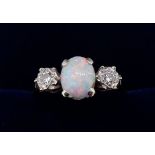 An 18 carat gold and platinum set opal ring, the oval cut opal flanked by two illusion set diamonds,