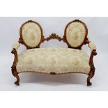 A Victorian mahogany twin oval backed settee with carved decoration on scroll supports, 122cm wide