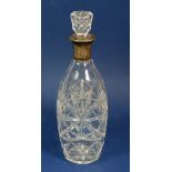 A cut glass decanter with silver collar