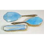A silver and enamel childs three piece dressing table set with mirror and brushes, Birmingham 1938