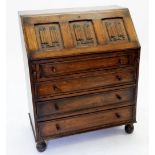 An oak Jacobean style bureau with linenfold carved decoration, the slope front over four drawers,