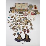 A box of badges including military cap badges
