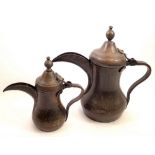 A graduated pair of Dallah Arabic Eastern coffee pots, largest 27cm high, pin hinge missing on