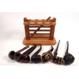 A wooden pipe stand with seven vintage pipes