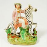 A Victorian Staffordshire zebra and rider group, 18.5cm tall