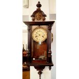 A 19th century mahogany cased small wall clock with mask to surmount, 72cm tall