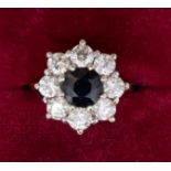 An 18 carat gold diamond and sapphire cluster ring, the central sapphire approx. 6.5mm diameter,