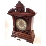 An American 19th century oak carved mantel clock with enamel chapter ring and carved case, 38cm tall