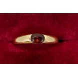 A gold ring set oval cut garnet, unmarked, size J , 2.8g