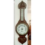 An oak barometer/thermometer by H Hughes and Son Ltd. 69cm tall