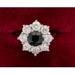An 18 carat gold diamond and sapphire cluster ring, the central sapphire approx. 6.5mm diameter,