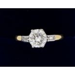 An 18 ct gold large solitaire diamond ring on baguette cut diamond shoulders, the central stone with