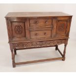 A small carved buffet sideboard with two drawers flanked by two cupboards all on stand with two