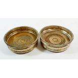 A pair of silver plated and wooden bottle coasters