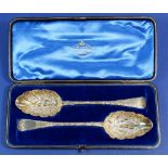 A pair of Victorian silver gilt serving spoons with embossed decoration by Goldsmiths &