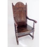 A late 17th century oak arch carved and panel back chair with solid seat and turned supports