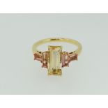 An 18 ct gold ring set central step cut yellow topaz flanked by two pairs of step cut pink topaz,