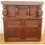 A 17th century oak court cupboard, the upper section with carved figure and parquetry decoration